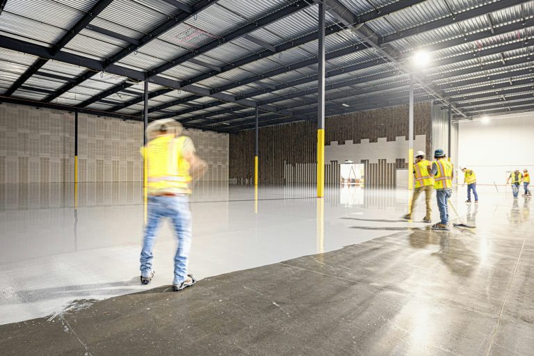 Crew finishing the floor of a steel-framed commercial building under construction