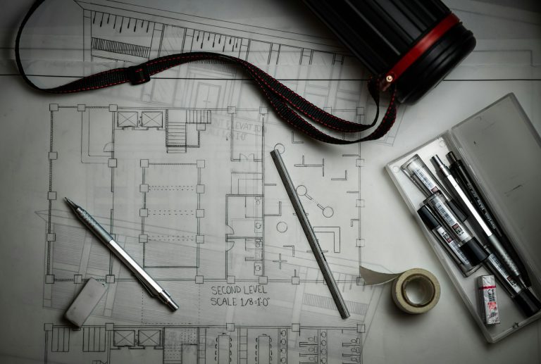 Commercial floor plan drawn to an imperial scale, with drafting tools laid across it