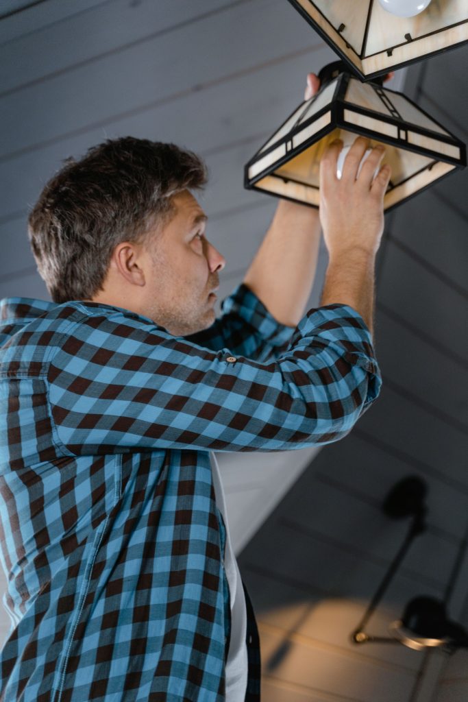 Electrician installing a ceiling light fixture in a home