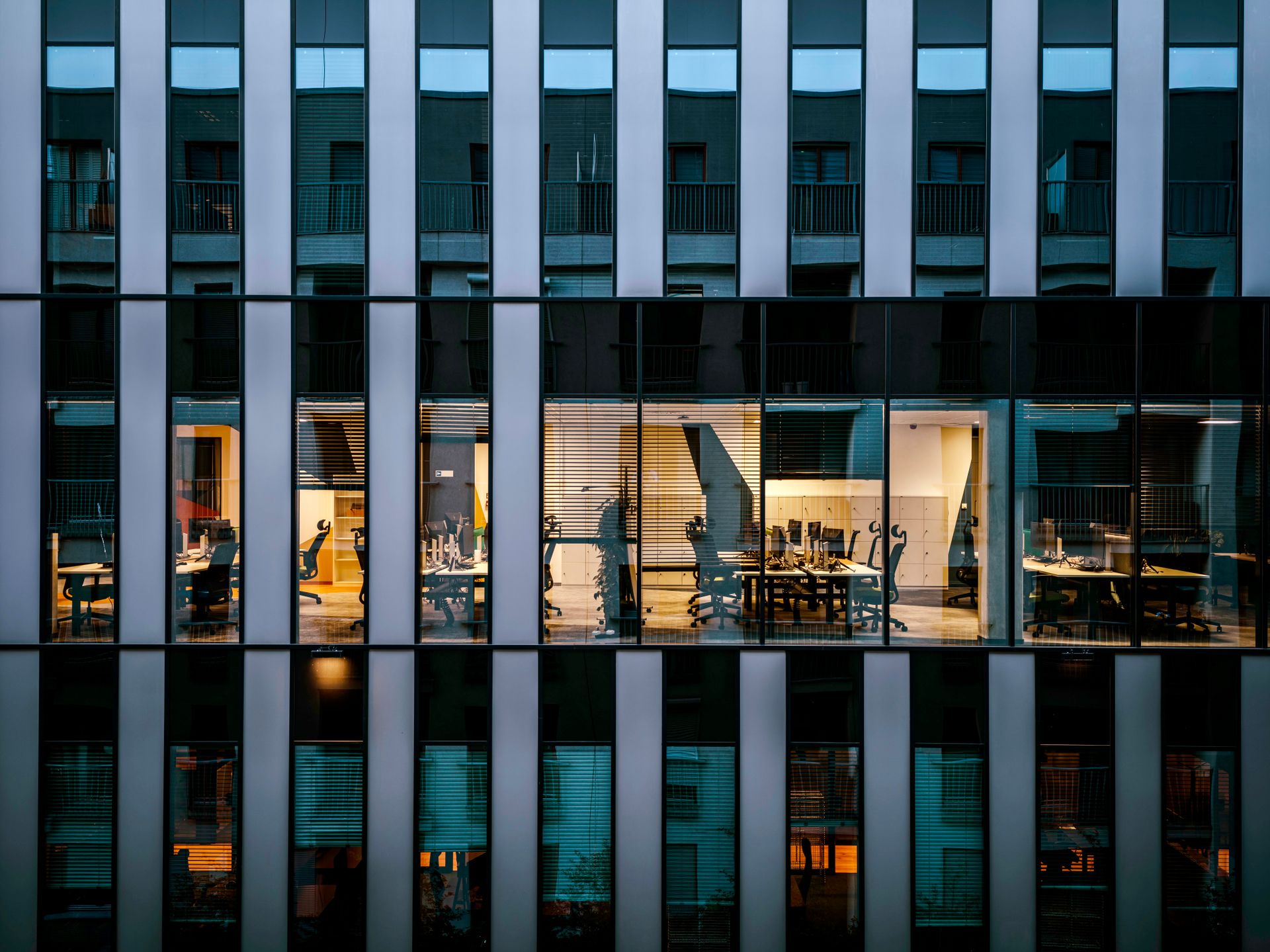 Lit office interiors seen through a glass facade