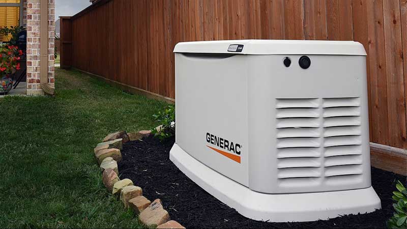Home standby generator installed on a pad beside a brick house